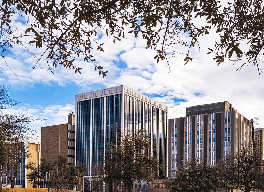 Odessa, TX - Midland Texas City Skyline and Downtown Skyscrapers With Dramatic Cloudy Blue Sky and Tree Branches